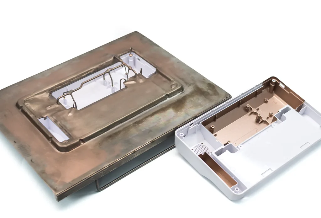 Plastic medical part that gets sprayed in a very intricate Nickel Electroform mask. A raw part in the mask itself is visible to the left; the finished/sprayed part is on the right.