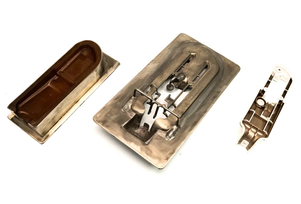From left to right: Cast urethane base fixture for part to sit in; nickel electroform custom masking tool; physical part sprayed using toolset.