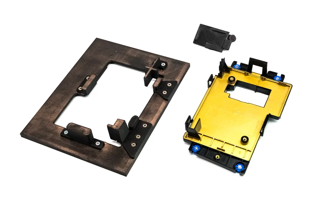 At left: a 3D-printed custom masking tool; EMI part completed using tool to the right. Above is another 3D-printed cap that is used in the center window of the part during spray.